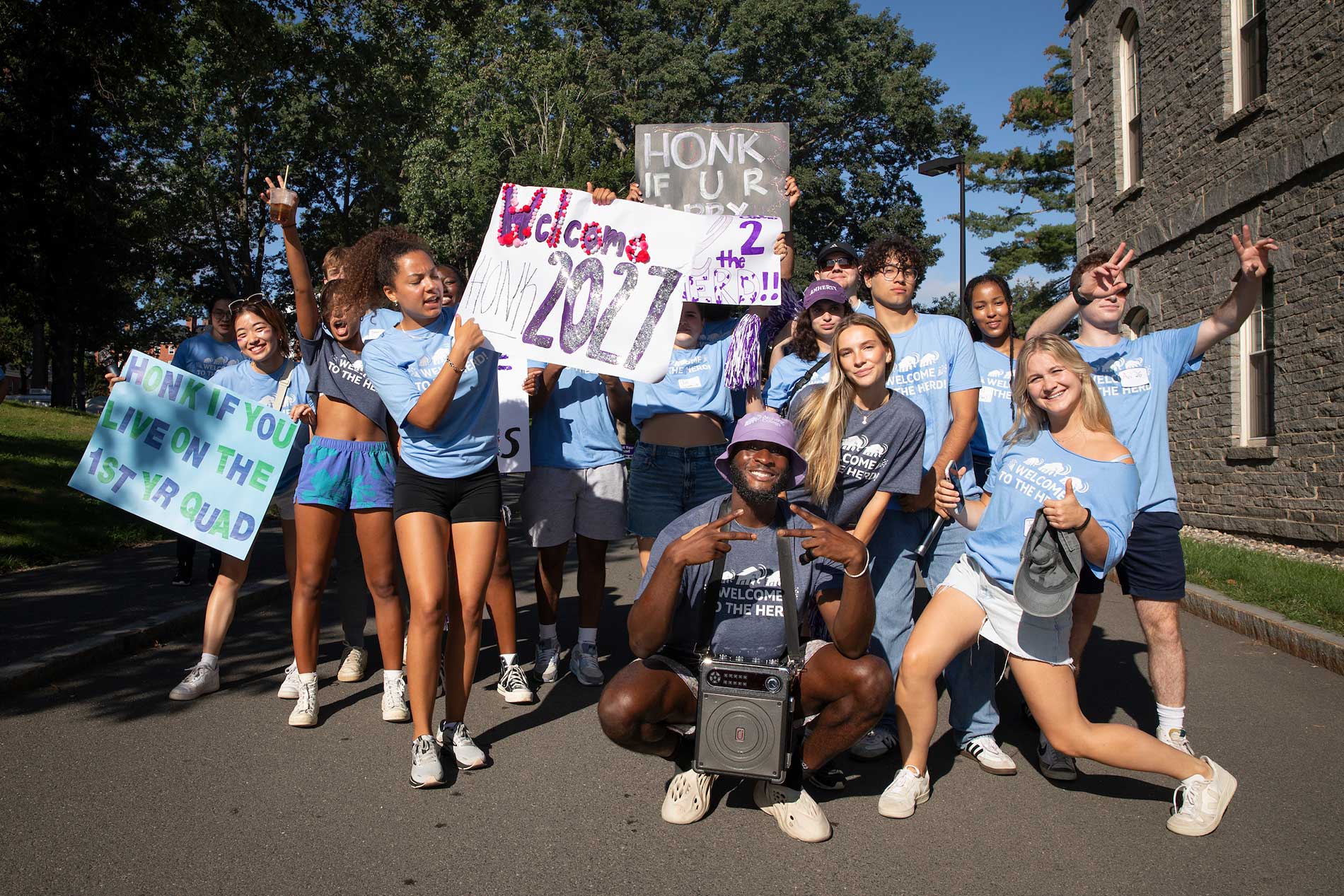 Orientation leaders holding welcome signs as new students arrive.