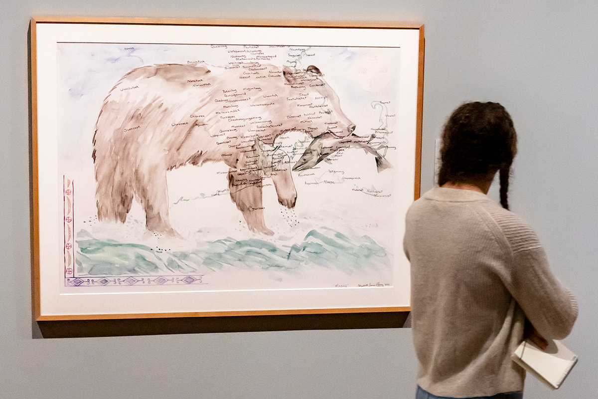A young woman looking at a painting of a bear in an art museum