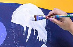A paintbrush painting a white cloud on a wall 