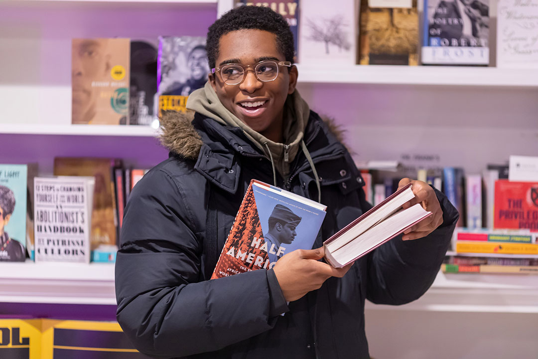 Daniel Mallory '25 receives is gifted several books from his professor during office hours.
