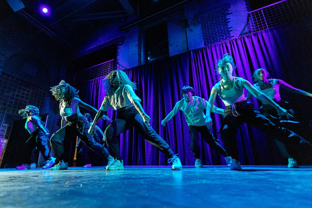 On a blue lit stage, Amherst students, members of DASAC, perform Sin City at the Powerhouse.