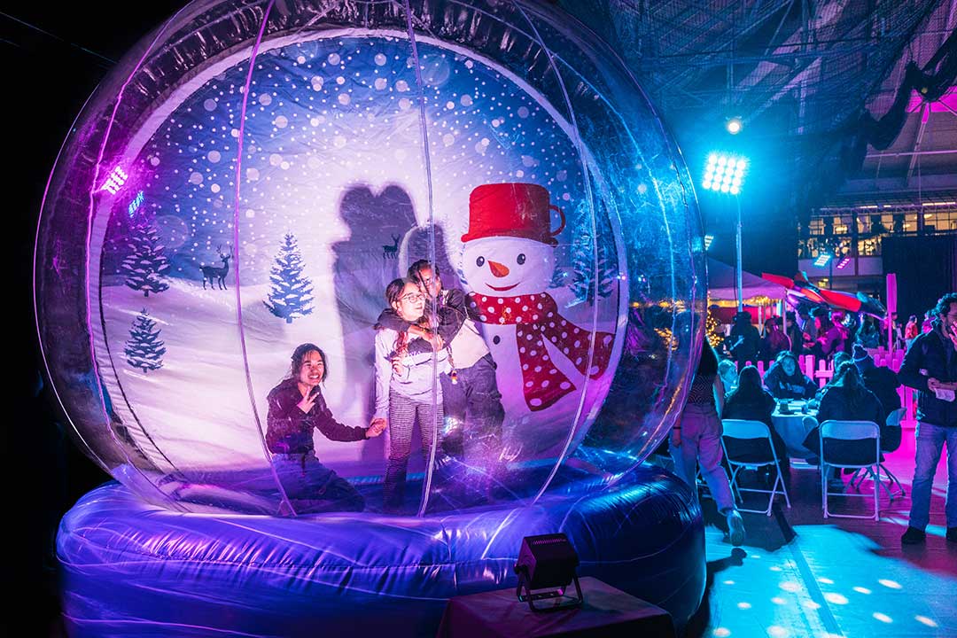 Three children pose for a photo inside a giant blow up snow globe.