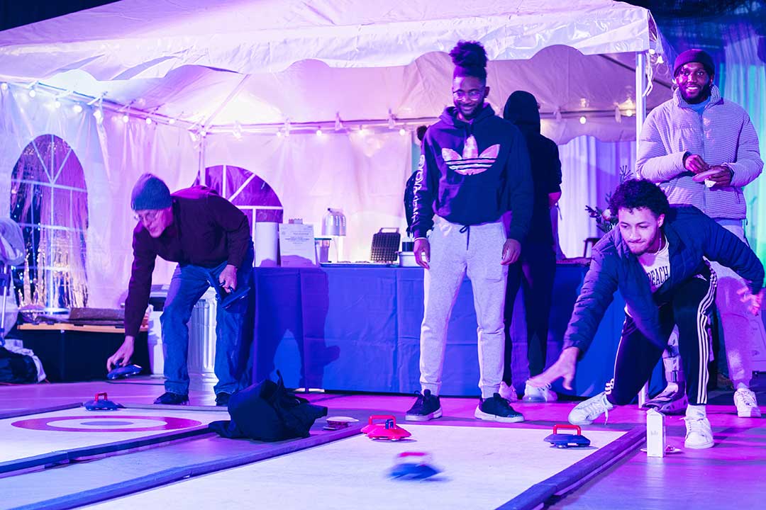 Several student play a game of curling on synthetic ice.